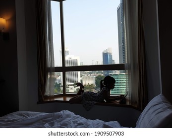 Jakarta, Indonesia - May 26, 2019: Sillhoute Of A Kid Playing Her Ipad, Looking Over Jakarta Skyline