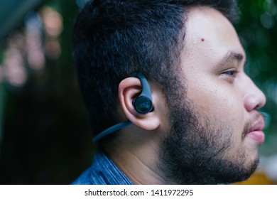 Jakarta, Indonesia - May 31, 2019: The Plantronics BackBeat Fit 2100 has a reflective finish to keep you visible at night and Always Aware eartips. Young man use wireless sport headphones.