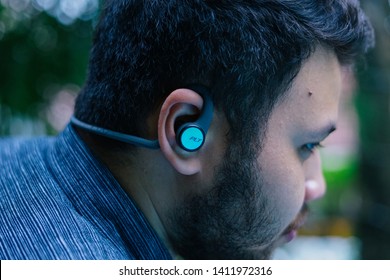 Jakarta, Indonesia - May 31, 2019: The Plantronics BackBeat Fit 2100 has a reflective finish to keep you visible at night and Always Aware eartips. Young man use wireless sport headphones.