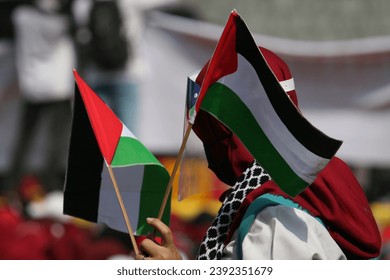 Jakarta, Indonesia - Mei 18, 2021 : A demonstrator carries a Palestinian flag during an action to defend Palestine in front of the United States Embassy, Jakarta, Indonesia, May 18, 2021.