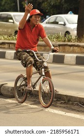 Jakarta, May 2011 - An Old Man Cycling On The Side Of The Road Celebrates The Hustle And Bustle Of The Pindapata Tradition, Before The Vesak Day.                     