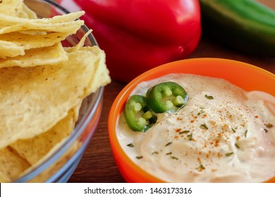 Jalapeno Ranch Dip In Orange Bowl Next To Large Glass Bowl Of Tortilla Chips And Fresh Ingredients