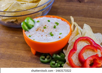 Jalapeno Ranch Dip In Orange Bowl Next To Large Glass Bowl Of Tortilla Chips And Fresh Ingredients