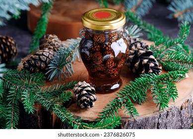 Jam from young pine cones in syrup on a background with pine branches.style rustic.selective focus