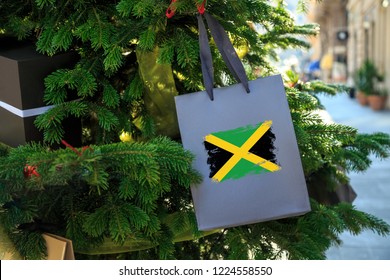 Jamaica flag printed on a Christmas shopping bag. Close up of a gift bag as a decoration on a Xmas tree on a street. New Year or Christmas shopping, local market sale and deals concept. 