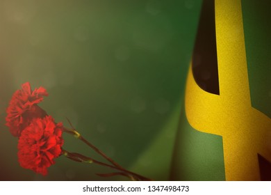 Jamaica Flag With Two Red Carnation Flowers For Honour Of Veterans Or Memorial Day On Teal, Sea-green Dark Velvet Background. Jamaica Glory To Heroes Of War Concept.