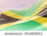 Jamaica national flag fluttering with birds. The flag blowing in beautiful soft sky. Jamaica national flag for independence day.