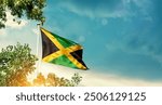 Jamaica national flag waving in the sky behind the tree. The flag blowing with beautiful sunlight. Jamaica national flag for independence day.