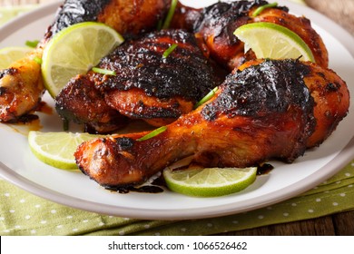 Jamaican food: jerk chicken drumstick with lime closeup on a plate on the table. horizontal