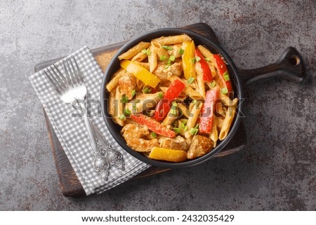 Jamaican Style Rasta Pasta Penne with Grilled Chicken and Bell Peppers closeup on the bowl on the wooden board. Horizontal top view from above
