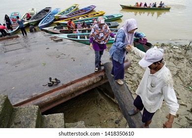 Jambi- Indonesia, 12 Mei 2019. A Woman Was Passing A Slippery Board Bridge On The Edge Of The Batanghari River After Crossing That Longest River In Sumatera Using A Colorful Traditional Boat.