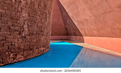 James Turrell Within Without skyspace artwork at NGA Canberra Australia. A pyramid with soft red ochre interior walls with a stupa made of basalt highlighted by turquoise water. On a sunny day.