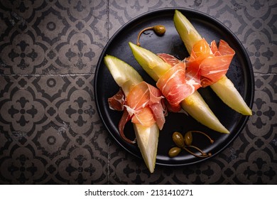 Jamon Serrano, Ham Or Prosciutto With Melon And Olives, A Traditional Spanish And Italian Appetizer On Plate, Top View