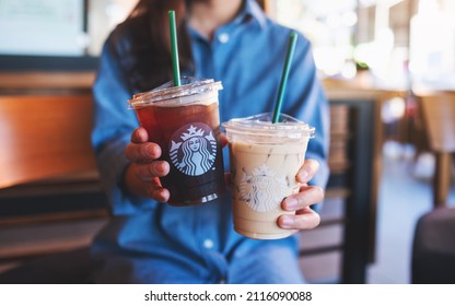 Jan 25th 2022 : Closeup of a woman holding or serving two glasses of iced coffee at Starbucks coffee shop, Chiang mai Thailand 