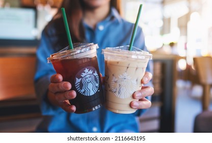 Jan 25th 2022 : Closeup of a woman holding or serving two glasses of iced coffee at Starbucks coffee shop, Chiang mai Thailand 
