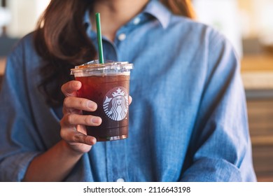 Jan 25th 2022 : Closeup of a woman holding and drinking iced coffee at Starbucks coffee shop, Chiang mai Thailan
