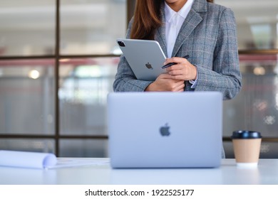 Jan 26th 2021 : A business woman holding and using Apple New Ipad Pro 2020 digital tablet with Apple MacBook Pro laptop computer in office, Chiang mai Thailand