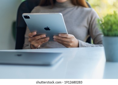 Jan 5th 2021 : A woman holding and using Apple New Ipad Pro 2020 digital tablet with Apple MacBook Pro laptop computer on the table, Chiang mai Thailand