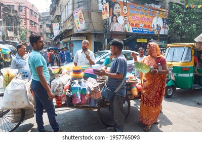 Janbazar, Kolkata, 03-27-2021: Buyers Standing Near A Market Vendor Selling Plastic Household Items In A Pull Cart, Inside A Crowded Marketplace. No One Is Wearing Any Protective Face Mask.