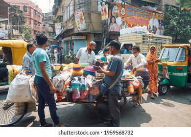 Janbazar, Kolkata, 03-27-2021: Buyers Standing Near A Market Vendor Selling Plastic Household Items In A Pull Cart, Inside A Crowded Marketplace. No One Is Wearing Any Protective Face Mask.