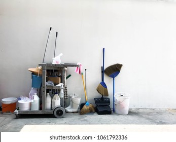 Janitor Cart With Equipment Or Tools For Cleaning Service In Office, Hotel Department Store, Factory And Company. Cleaning Cart With Brooms, Mop, Swab, Bucket, Floor Cleaner In Empty Space Background.