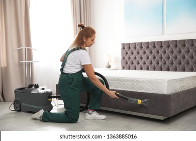 Janitor Cleaning Bed With Professional Equipment In Room