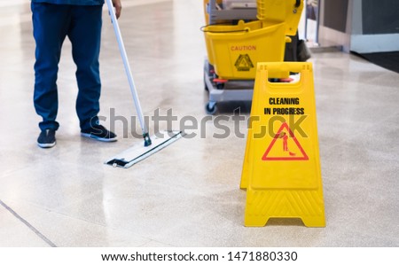 Janitor Cleaning Floor In Front Of Yellow Caution 'Cleaning in progress'. Cleaning service in public area. Foto d'archivio © 
