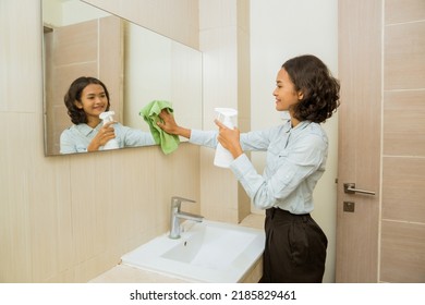 Janitor Cleaning The Mirror, Spraying And Wiping The Mirror With Cloth In The Bathroom