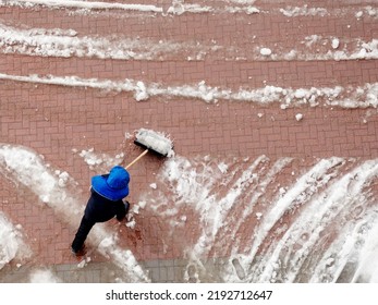 The Janitor Clears The Snow With A Shovel. View From Above. Wet Snow In The Yard. Top View