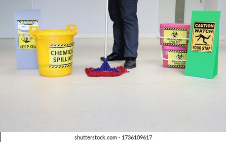 Janitor Male Cleaning Floor In Medical Service Room Or Laboratory With Caution Tag Sign Watch Your Step And Biohazard Spill Kit, Chemical Spill Kit Yellow Bucket For Response Chemical Spill Out Cases.