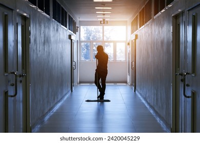 Janitor man mopping floor in hallway office building or walkway after school and classroom silhouette work job with sun light background. Poor people working job.