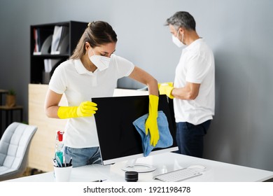 Janitor Service Woman Cleaning Monitor On Desk In Face Mask