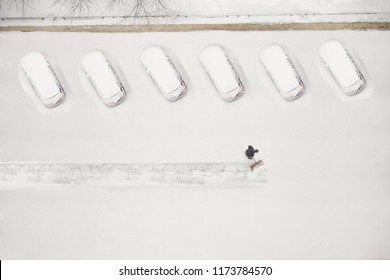 Janitor With A Shovel Cleans The Snow Of City Street. View From Above 