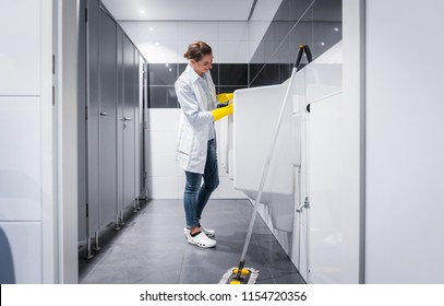 Janitor Woman Cleaning Urinals In Public Mens Toilet 