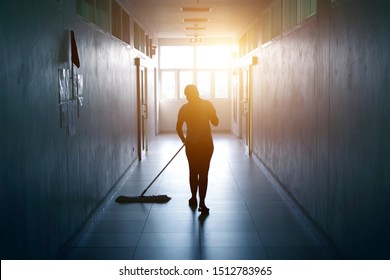 Janitor woman mopping floor in hallway office building or walkway after school and classroom silhouette work job with sun light background. Poor people working job.