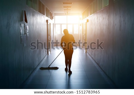 Janitor woman mopping floor in hallway office building or walkway after school and classroom silhouette work job with sun light background. Poor people working job. Foto d'archivio © 