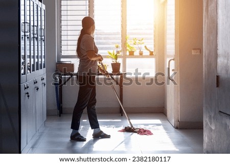 Janitor woman mopping floor in hallway office building or walkway after school or classroom with blank copy space. Housekeeper working job with sun light background.