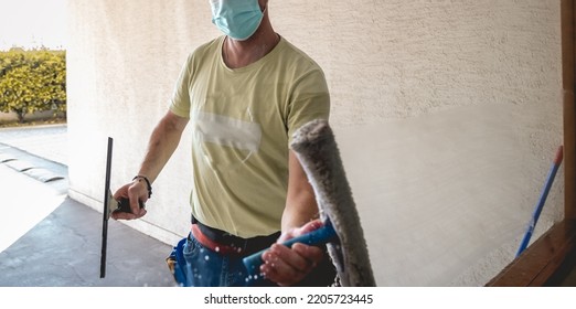 Janitor Worker Guy With Mask Cleaning Big Window Glass With Cleaning Tools In The Day