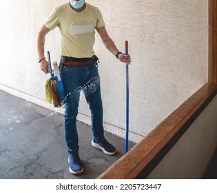 Janitor Worker Guy With Mask Cleaning Big Window Glass With Cleaning Tools In The Day