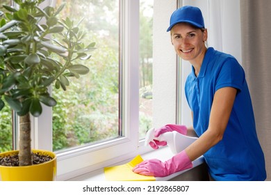 Janitorial Cleaning Services. Smiling Female Worker Disinfecting Apartment Windowsill 