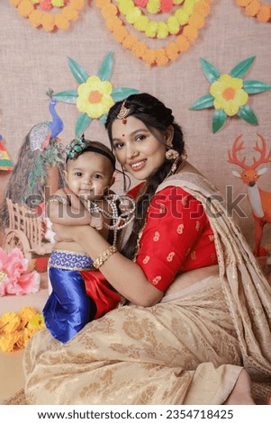 Janmashtami Concept. Mother sitting with her cute baby boy dressed up as little krishna.