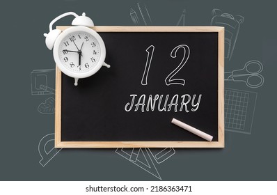 january 12. 12th day of month, calendar date. Blackboard with piece of chalk and white alarm clock on green background. Concept of day of year, time planner, winter month.