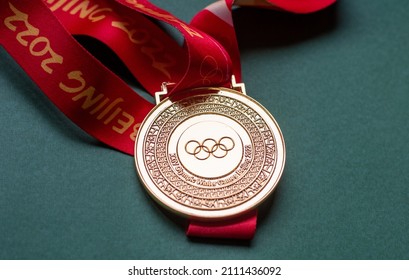 January 14, 2022, Beijing, China. Gold medal of the XXIV Olympic Winter Games on a green background.