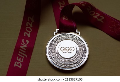 January 14, 2022, Beijing, China. Gold medal of the XXIV Olympic Winter Games on a yellow background.