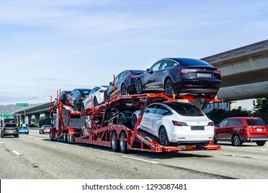 January 19, 2019 San Bruno / CA / USA - Car transporter carries Tesla Model 3 new vehicles along the highway in San Francisco bay area, back view of the trailer; 