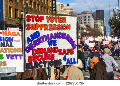 January 19, 2019 San Francisco / CA / USA - Participant to the Women's March event holds sign referencing voting suppression, gerrymandering while marching on Market street in downtown San Francisco