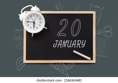 january 20. 20th day of month, calendar date. Blackboard with piece of chalk and white alarm clock on green background. Concept of day of year, time planner, winter month.