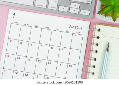January 2022 calendar sheet with keyboard computer on pink background.
