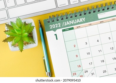 January 2022 desk calendar and diary with keyboard computer on yellow background.