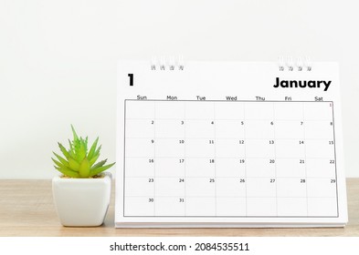 The January 2022 Desk Calendar And Small Plant On Wooden Table.